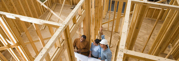 Couple inside early construction home with construction worker going over plans
